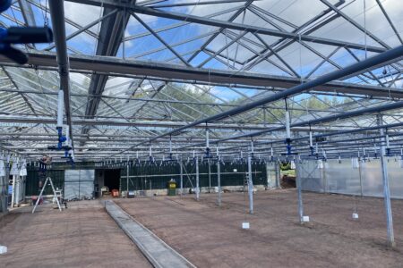 Large commercial greenhouse under construction with an irrigation system installed overhead